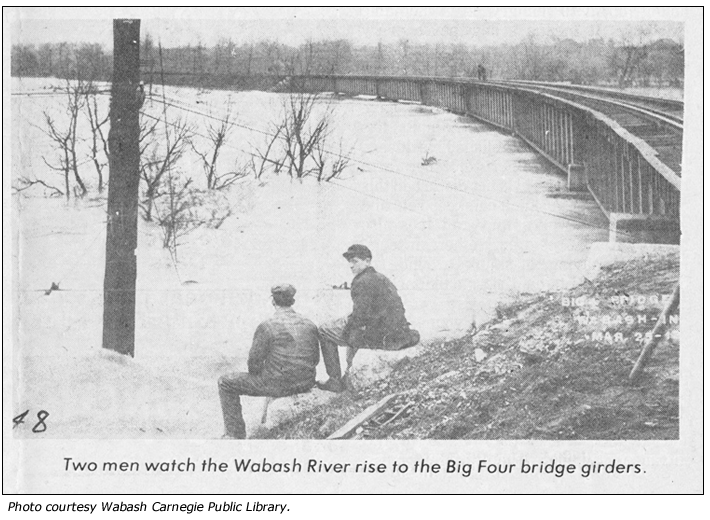 Two men watch the Wabash River rise to the Big Four bridge girders near Wabash, IN
